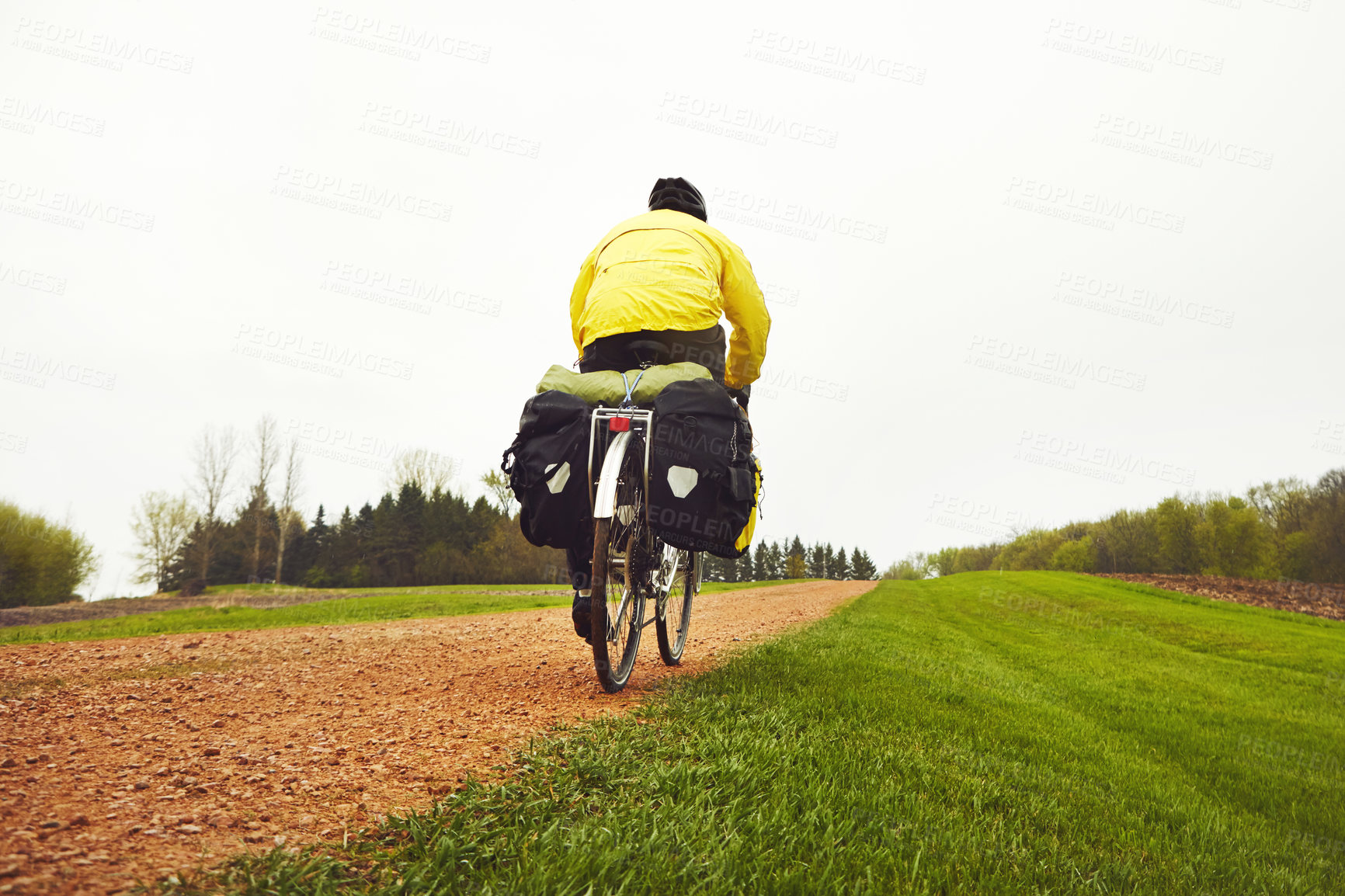 Buy stock photo Rearview shot of a male cyclist enjoying a bike ride on a wet winter's morning