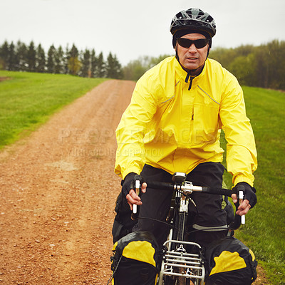 Buy stock photo Cropped shot of a male cyclist enjoying a bike ride on a wet winter's morning