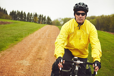 Buy stock photo Cropped shot of a male cyclist enjoying a bike ride on a wet winter's morning