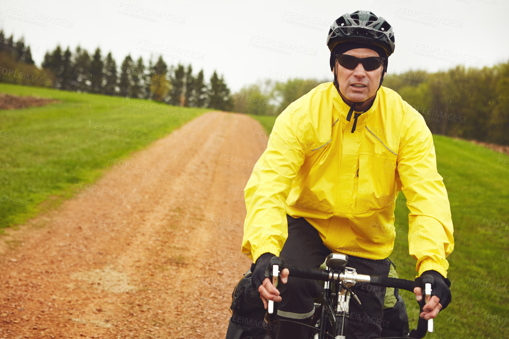 Buy stock photo Cropped shot of a male cyclist enjoying a bike ride on a wet winter's morning