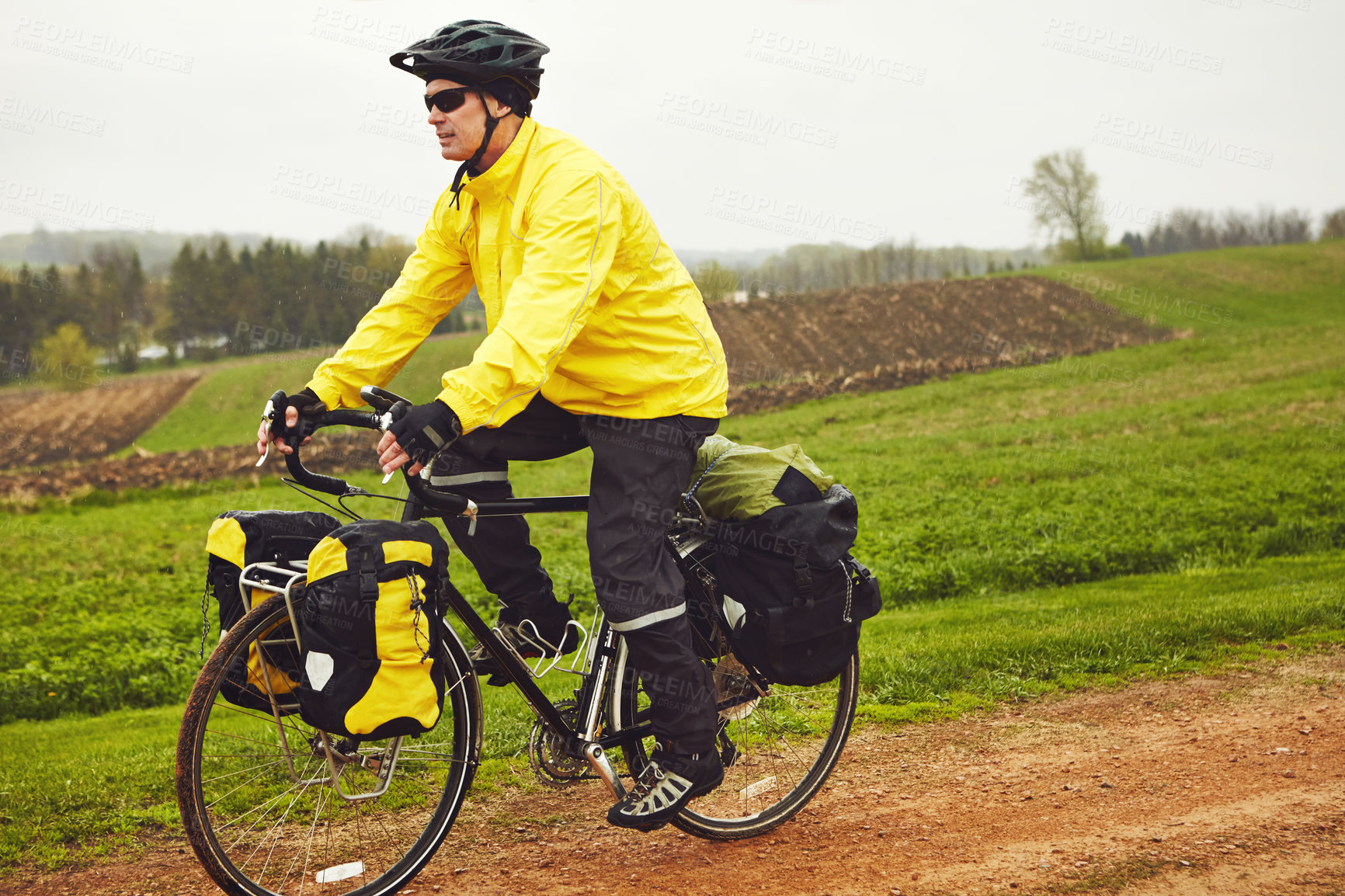 Buy stock photo Cropped shot of a male cyclist enjoying a bike ride on a wet winter's morning