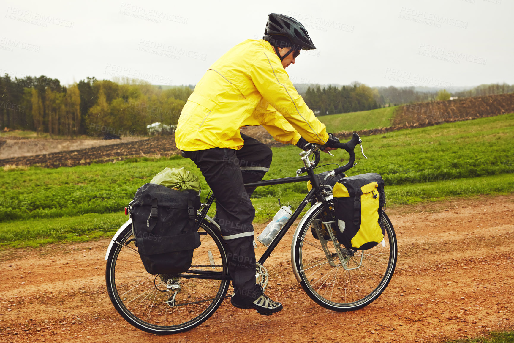 Buy stock photo Full length shot of a male cyclist enjoying a bike ride on a wet winter's morning