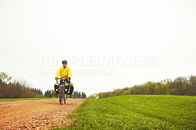 Buy stock photo Full length shot of a male cyclist enjoying a bike ride on a wet winter's morning