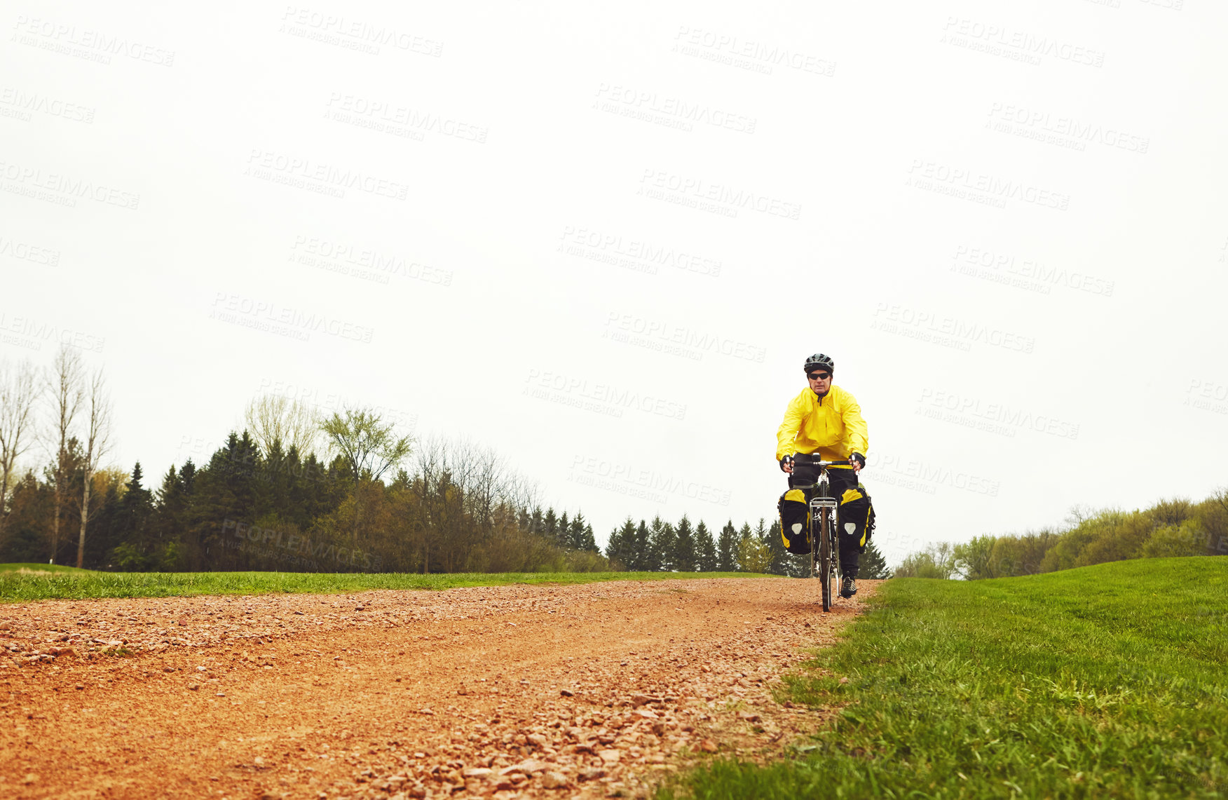 Buy stock photo Full length shot of a male cyclist enjoying a bike ride on a wet winter's morning