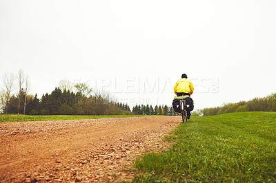 Buy stock photo Rearview shot of a male cyclist enjoying a bike ride on a wet winter's morning