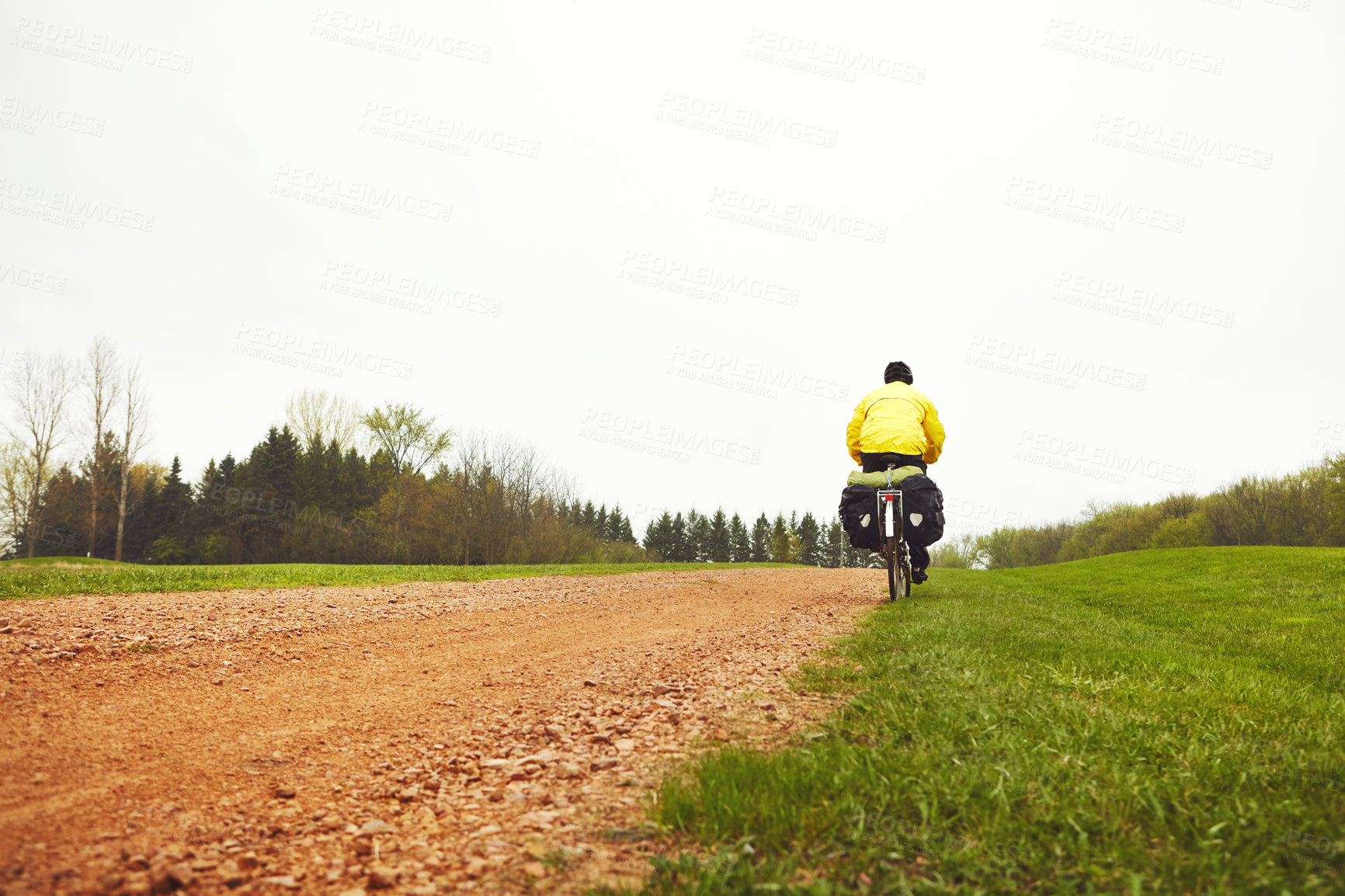 Buy stock photo Rearview shot of a male cyclist enjoying a bike ride on a wet winter's morning