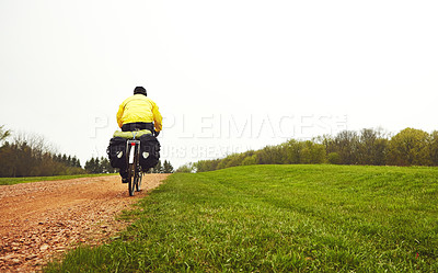 Buy stock photo Rearview shot of a male cyclist enjoying a bike ride on a wet winter's morning