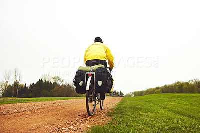 Buy stock photo Rearview shot of a male cyclist enjoying a bike ride on a wet winter's morning