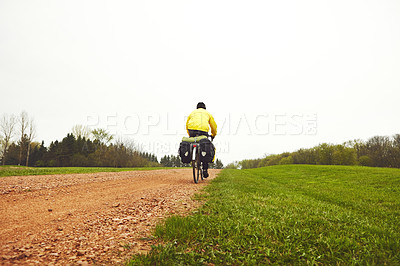 Buy stock photo Rearview shot of a male cyclist enjoying a bike ride on a wet winter's morning