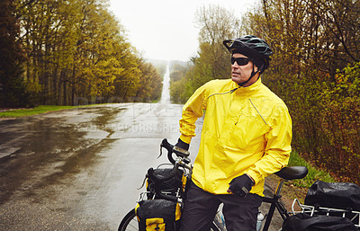 Buy stock photo Cropped shot of a male cyclist enjoying a bike ride on a wet winter's morning