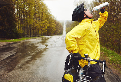 Buy stock photo Cropped shot of a male cyclist enjoying a bike ride on a wet winter's morning