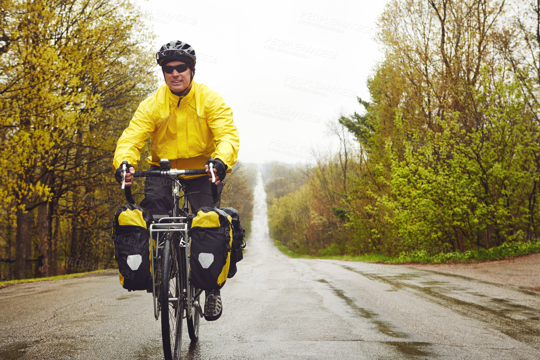 Buy stock photo Cropped shot of a male cyclist enjoying a bike ride on a wet winter's morning