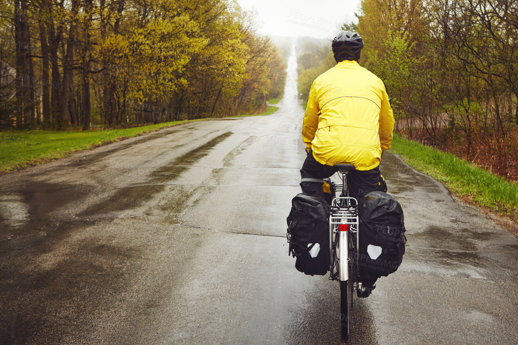 Buy stock photo Rearview shot of a male cyclist enjoying a bike ride on a wet winter's morning