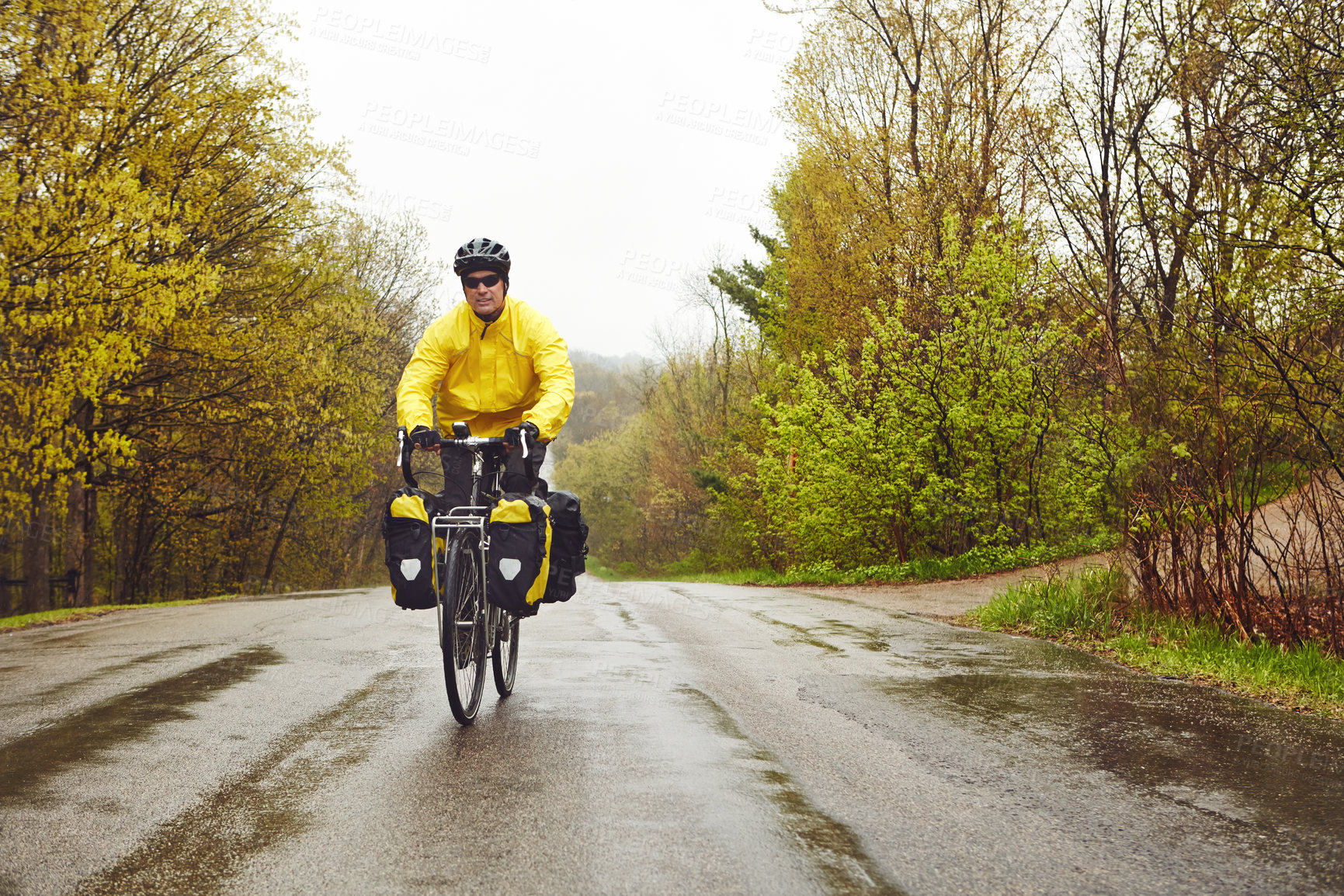 Buy stock photo Full length shot of a male cyclist enjoying a bike ride on a wet winter's morning