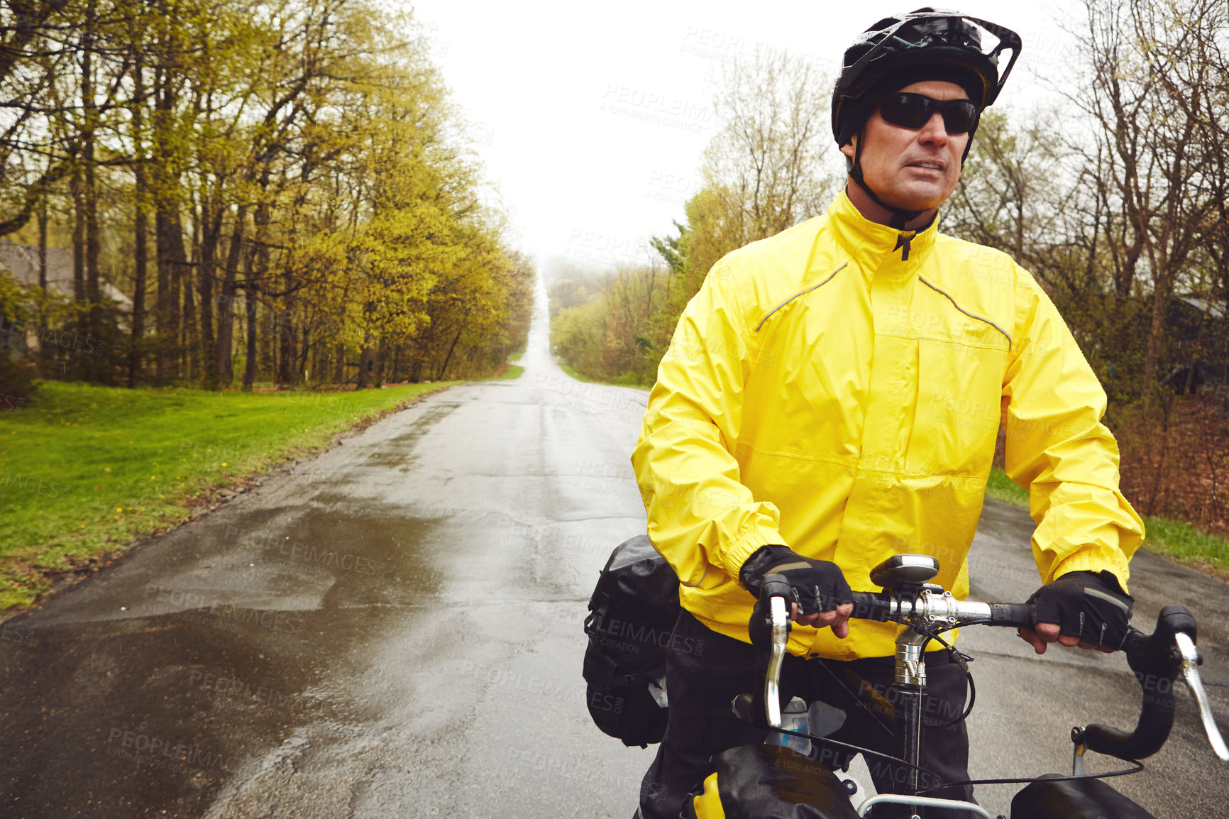 Buy stock photo Cropped shot of a male cyclist enjoying a bike ride on a wet winter's morning