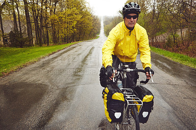 Buy stock photo Cropped shot of a male cyclist enjoying a bike ride on a wet winter's morning