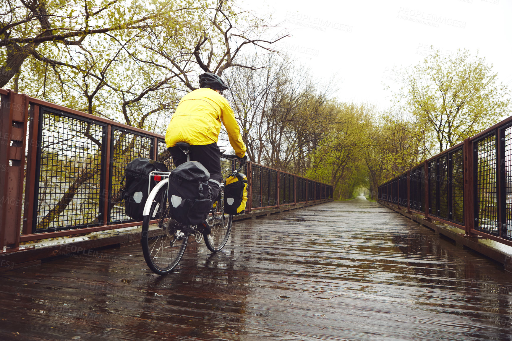 Buy stock photo Rearview shot of a male cyclist enjoying a bike ride on a wet winter's morning