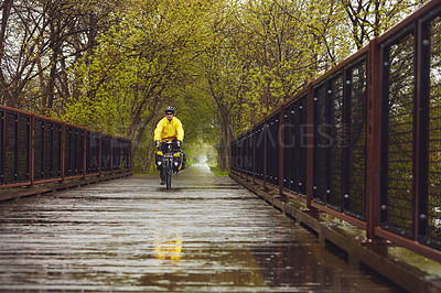 Buy stock photo Full length shot of a male cyclist enjoying a bike ride on a wet winter's morning