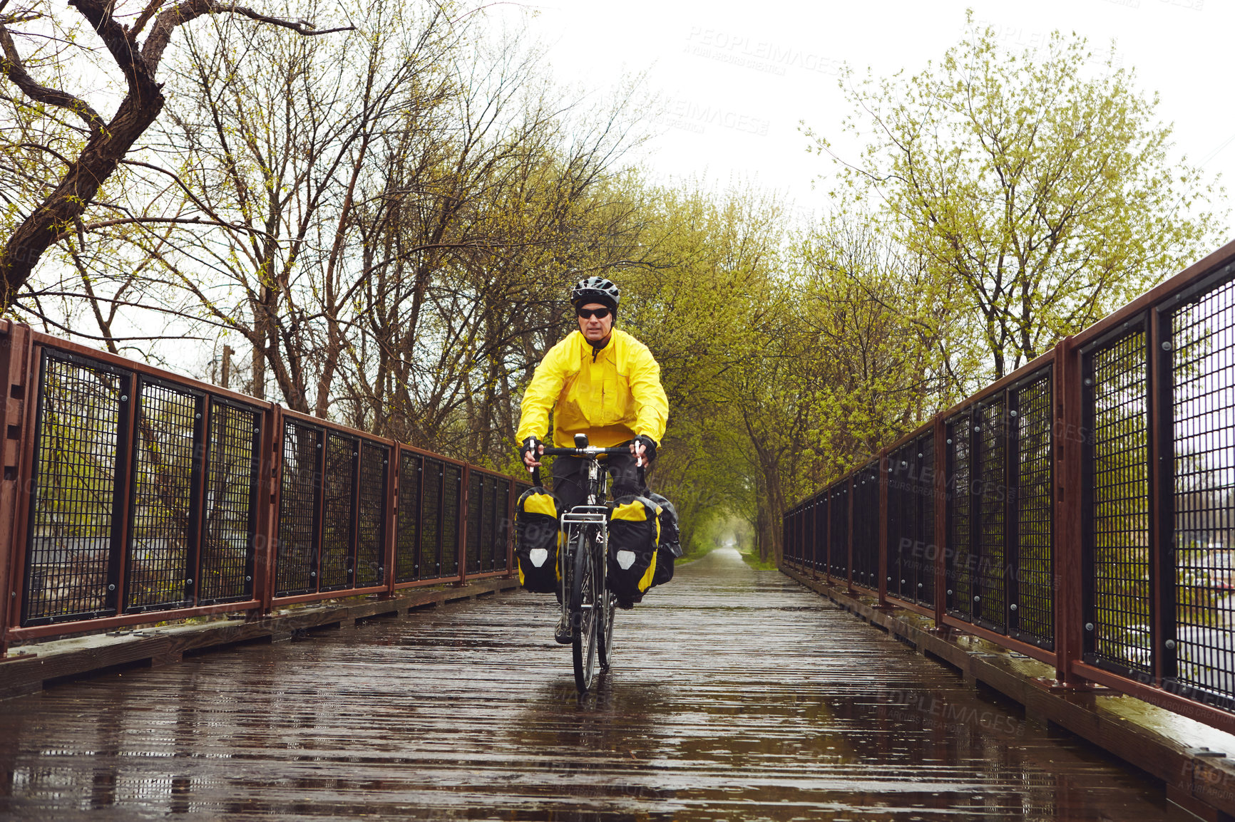 Buy stock photo Full length shot of a male cyclist enjoying a bike ride on a wet winter's morning