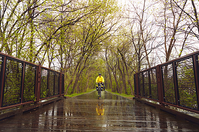 Buy stock photo Full length shot of a male cyclist enjoying a bike ride on a wet winter's morning