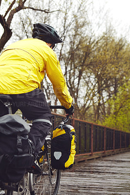 Buy stock photo Rearview shot of a male cyclist enjoying a bike ride on a wet winter's morning