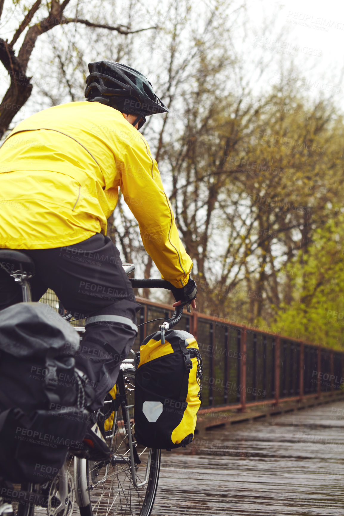 Buy stock photo Rearview shot of a male cyclist enjoying a bike ride on a wet winter's morning