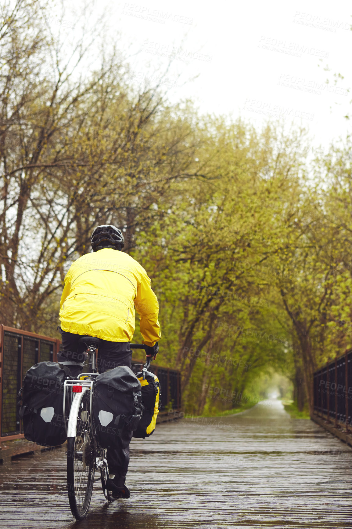 Buy stock photo Rearview shot of a male cyclist enjoying a bike ride on a wet winter's morning