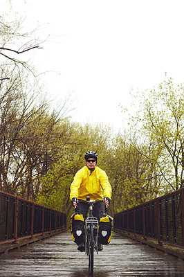 Buy stock photo Full length shot of a male cyclist enjoying a bike ride on a wet winter's morning