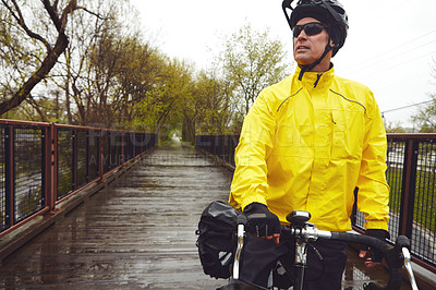 Buy stock photo Cropped shot of a male cyclist enjoying a bike ride on a wet winter's morning