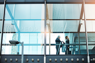 Buy stock photo Shot of a businessman and businesswoman having a discussion in a modern glass office