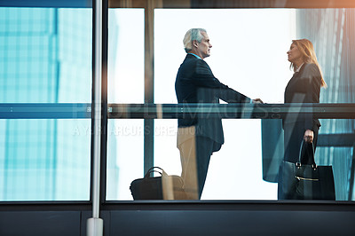 Buy stock photo Shot of a businessman and businesswoman shaking hands in a modern glass office