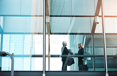 Buy stock photo Shot of a businessman and businesswoman shaking hands in a modern glass office