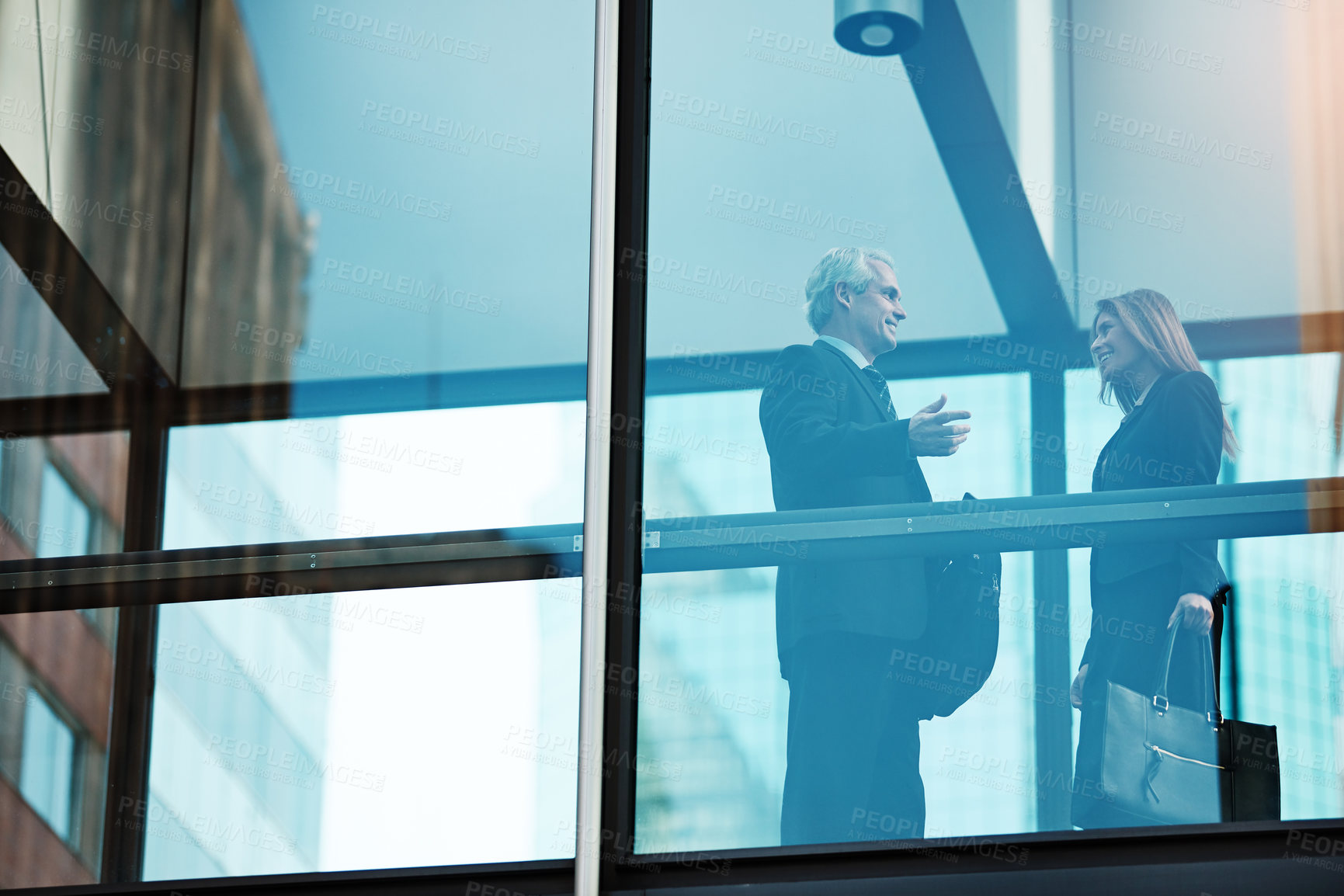 Buy stock photo Shot of a businessman and businesswoman having a discussion in a modern glass office