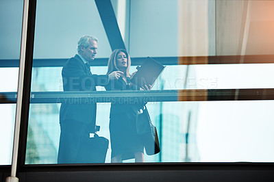 Buy stock photo Shot of a businessman and businesswoman having a discussion in a modern glass office