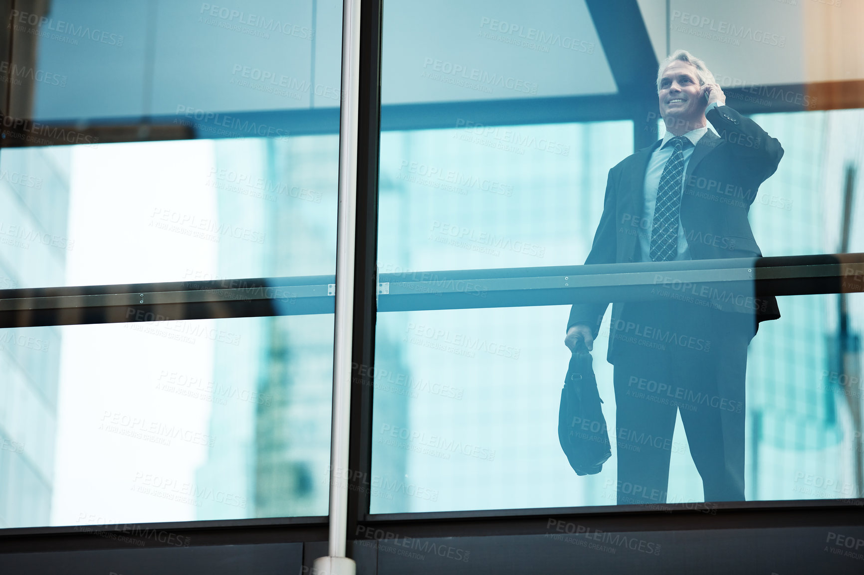 Buy stock photo Shot of a mature businessman using a mobile phone in a modern glass office