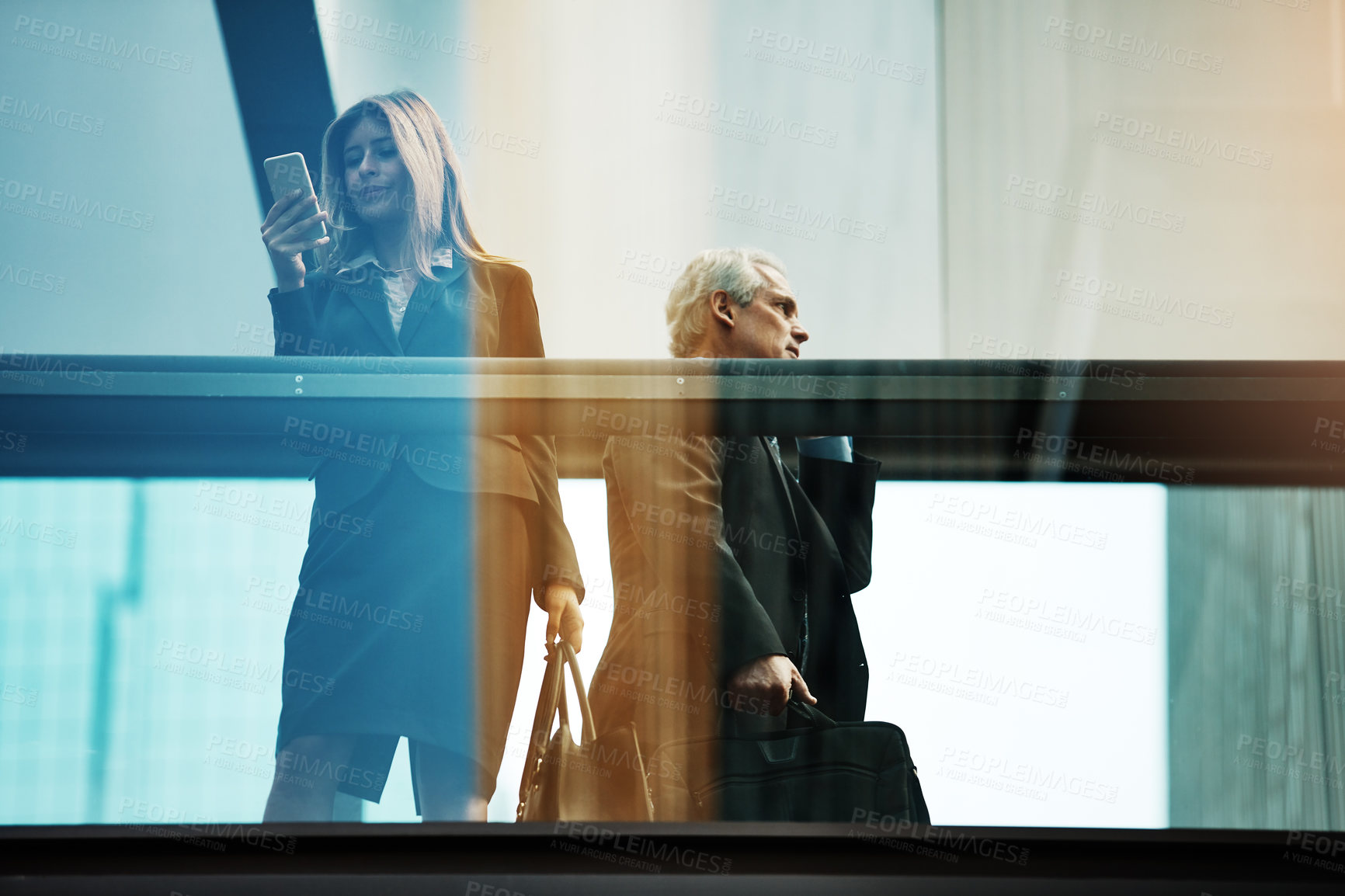 Buy stock photo Shot of businesspeople using their mobile phones in a modern glass office