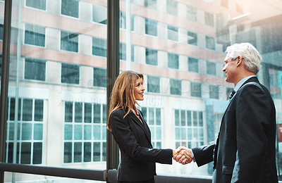 Buy stock photo Shot of a businessman and businesswoman shaking hands in a modern office