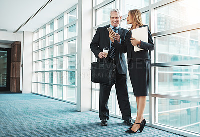 Buy stock photo Shot of a businessman and businesswoman using a mobile phone together in a modern office
