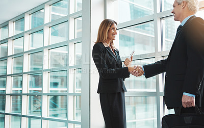 Buy stock photo Shot of a businessman and businesswoman shaking hands in a modern office