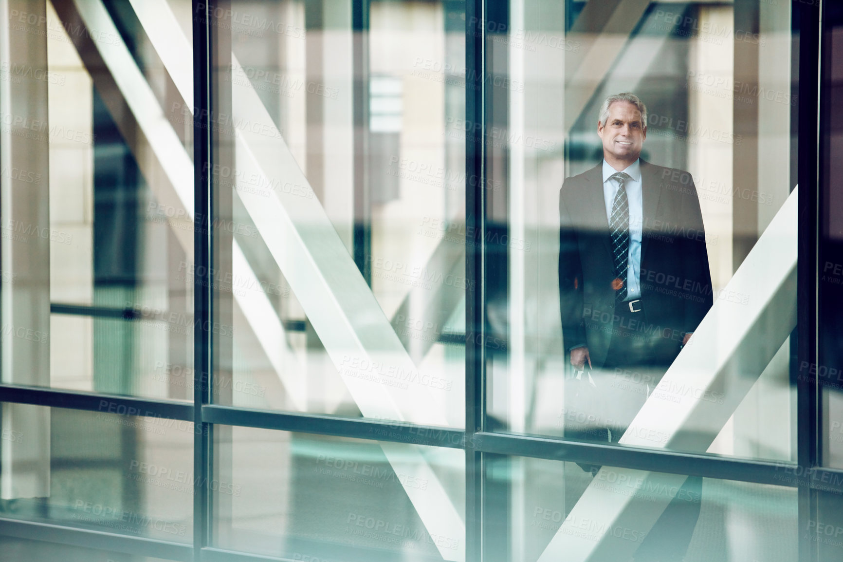 Buy stock photo Portrait of a mature businessman looking out of the window in a modern glass office