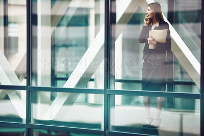 Buy stock photo Shot of a businesswoman using a mobile phone in a modern glass office