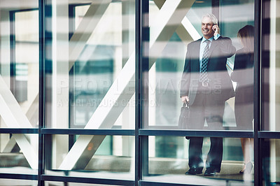 Buy stock photo Shot of a mature businessman using a mobile phone in a modern glass office