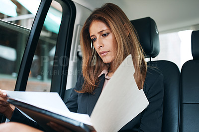 Buy stock photo Shot of a mature businesswoman going through paperwork in the back seat of a car