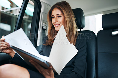 Buy stock photo Shot of a mature businesswoman going through paperwork in the back seat of a car