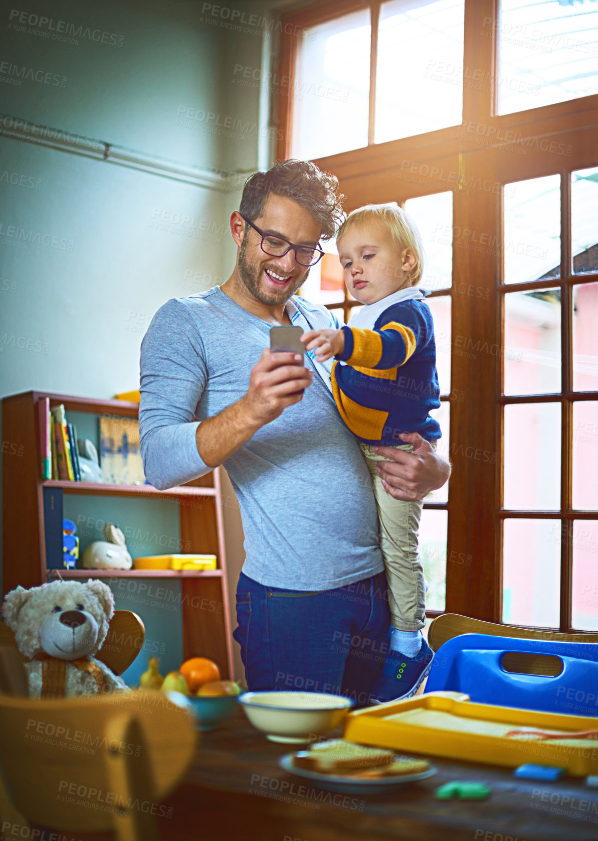 Buy stock photo Cropped shot of a single father using his cellphone and holding his son at home