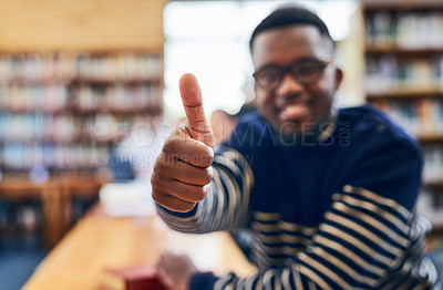 Buy stock photo Shot of a student showing thumbs up while sitting in the library