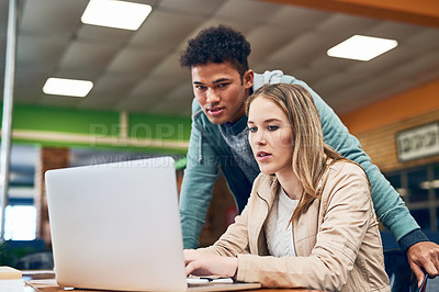 Buy stock photo Shot of a young man looking on while a female student works on a laptop