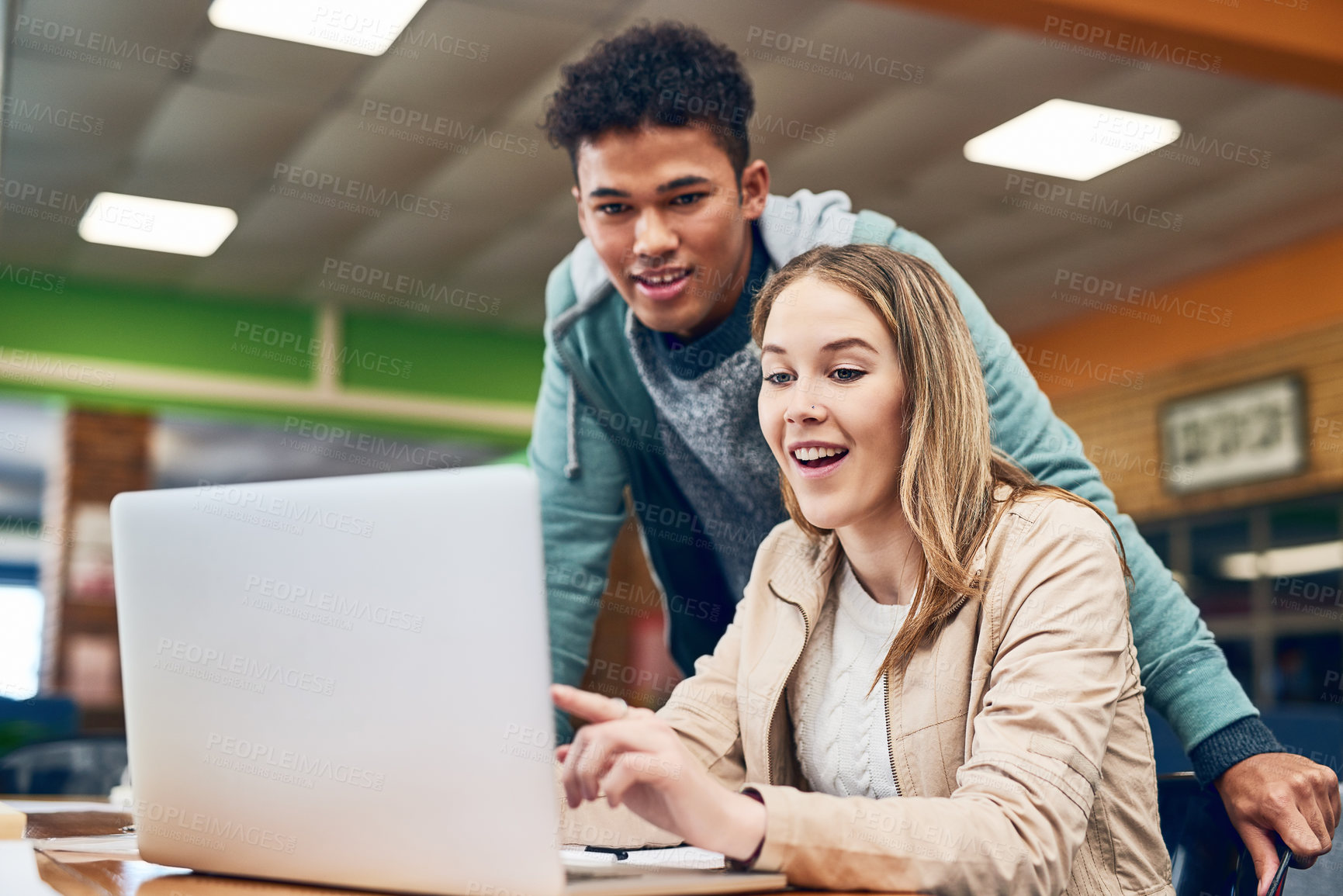 Buy stock photo Shot of a young man looking on while a female student works on a laptop