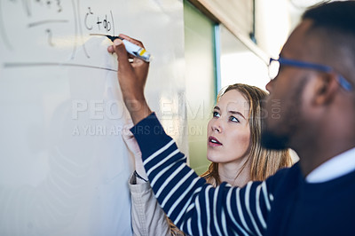 Buy stock photo Shot of a young woman looking on as a young man writes on a whiteboard