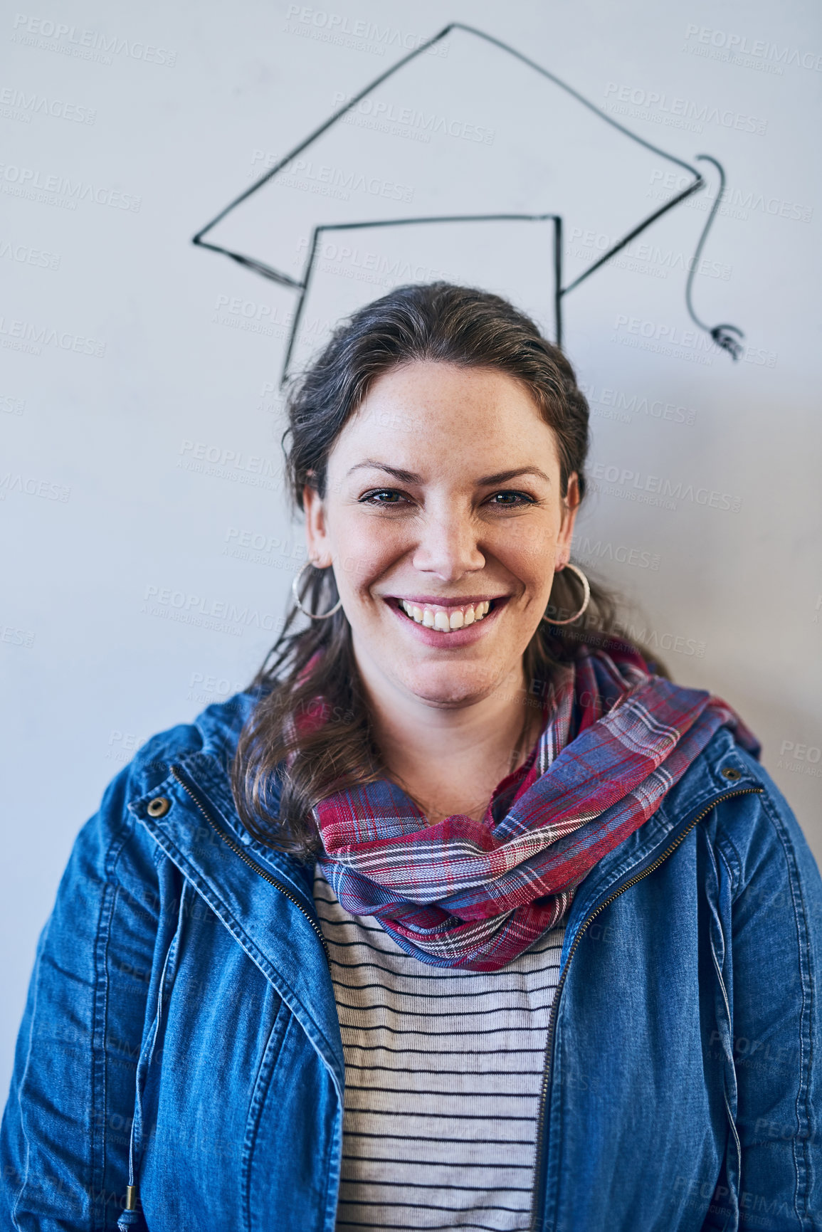 Buy stock photo Cropped shot of a young university student standing against a whiteboard with a graduation cap drawn on it